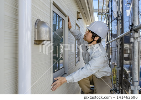 一名男工人正在檢查完工的外牆和窗框。 141462696