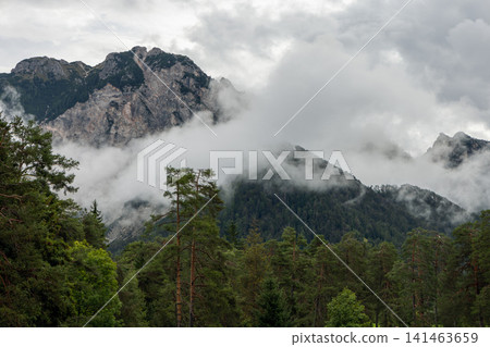 Rugged Dolomite crags wrapped in clouds above conifer forest, near San Vigilio di Marebbe Rugged Dolomite crags wrapped in clouds above conifer forest, near San Vigilio di Marebbe 141463659