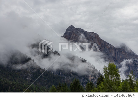 Dolomite peak appearing through dense fog above dark forest, near San Vigilio di Marebbe Dolomite peak appearing through dense fog above dark forest, near San Vigilio di Marebbe 141463664