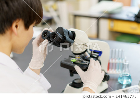 Close-up of a young Japanese man's hands looking through a microscope. Photo courtesy of Denpa Gakuen Educational Foundation, Tokyo Electronics College. Close-up of a young Japanese man's hands looking through a microscope. Photo courtesy of Denpa Gakuen Educational Foundation, Tokyo Electronics College. 141463773