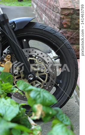 Front Wheel Of Modern Street Motorbike Near City Planter In Front Of Entrance To Residential Building. Motorcycle Parking Vertical Stock Image  141463799