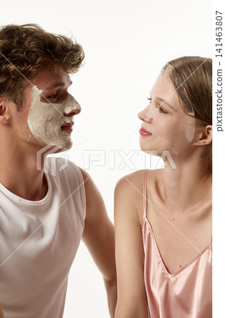 Side portrait of young woman looking at boyfriend wearing full facial mask Side portrait of young woman looking at boyfriend wearing full facial mask 141463807