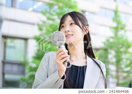 Japanese woman using a handheld fan Japanese woman using a handheld fan 141464406