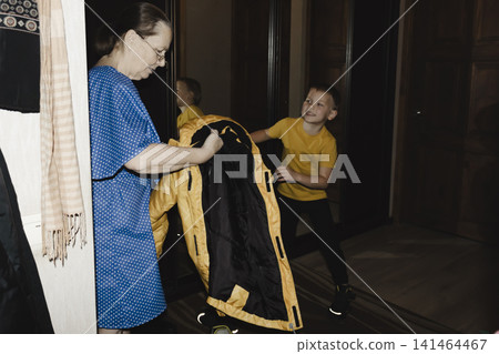 loving grandmother gently helps her grandson take off his coat he returns home, her face lit with quiet joy and warmth tender, everyday captures deep bond family comfort home simple pleasure being loving grandmother gently helps her grandson take off his coat he returns home, her face lit with quiet joy and warmth tender, everyday captures deep bond family comfort home simple pleasure being 141464467