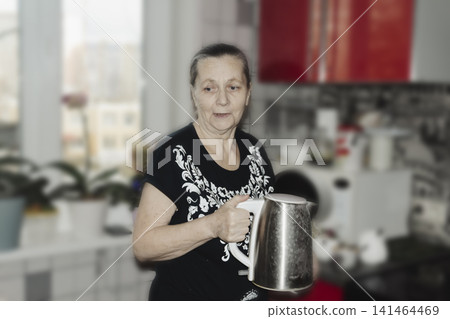 elderly woman casual holds sleek stainless steel kettle her gentle smile radiating warmth homeliness comforting scene evokes simple pleasures tea time, quiet domesticity soothing rituals everyday life elderly woman casual holds sleek stainless steel kettle her gentle smile radiating warmth homeliness comforting scene evokes simple pleasures tea time, quiet domesticity soothing rituals everyday life 141464469