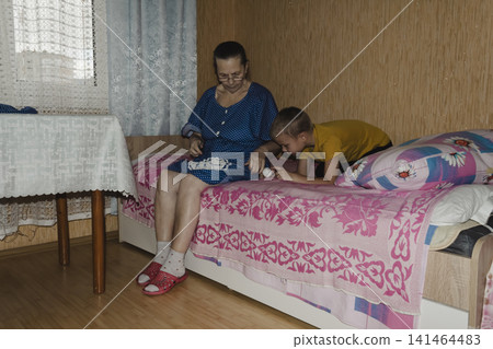 grandmother blue top patiently shows grandson how knit, her hands guiding share quiet, meaningful moment tender scene highlights beauty passing down traditions warmth family ties joy learning together grandmother blue top patiently shows grandson how knit, her hands guiding share quiet, meaningful moment tender scene highlights beauty passing down traditions warmth family ties joy learning together 141464483