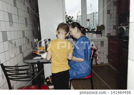 grandmother in blue dress her grandson striped shirt share warm cup tea cozy kitchen table quiet smiles capturing gentle bond family comfort home simple joy spending time together over familiar ritual 141464498