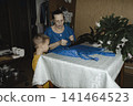 gentle grandmother blue top patiently shows her young grandson how sew piece fabric focused collaboration capturing warmth family learning passing traditions quiet joy creating something together 141464523