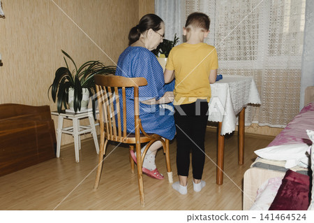 gentle grandmother blue top patiently shows her young grandson how sew piece fabric focused collaboration capturing warmth family learning passing traditions quiet joy creating something together 141464524