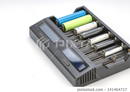 Universal multi bay smart battery charger loaded with various rechargeable batteries including AA AAA AAAA alkaline and colorful 18650 lithium ion cells arranged neatly in slots on white background Universal multi bay smart battery charger loaded with various rechargeable batteries including AA AAA AAAA alkaline and colorful 18650 lithium ion cells arranged neatly in slots on white background 141464717