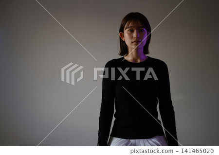 聚光燈下,一位身穿黑衣的女子沐浴在光芒中。 聚光燈下,一位身穿黑衣的女子沐浴在光芒中。 141465020