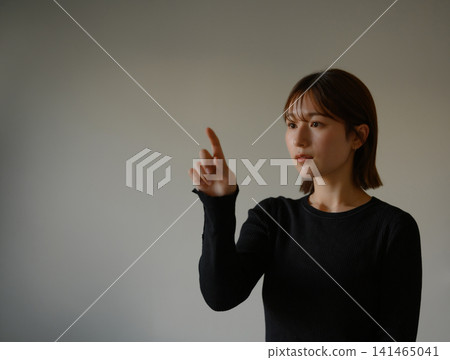 A woman touching the air with her fingers 141465041