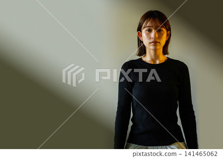 一束聚光燈照在一位身穿黑衣的女子身上。 一束聚光燈照在一位身穿黑衣的女子身上。 141465062