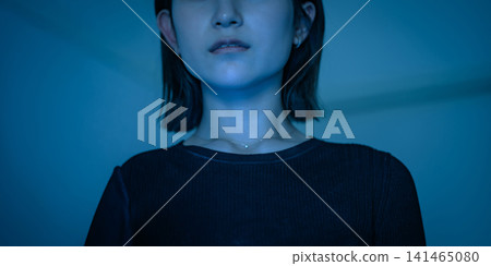 A close-up of a woman's face bathed in blue light. A close-up of a woman's face bathed in blue light. 141465080