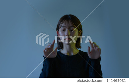 A woman trying to grasp something with both hands. A woman trying to grasp something with both hands. 141465081