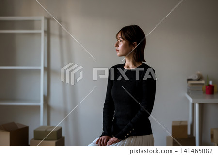 A young woman sitting in a chair, looking out the window. A young woman sitting in a chair, looking out the window. 141465082