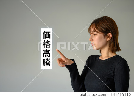 A young woman pointing her finger, against a simple background. A young woman pointing her finger, against a simple background. 141465110