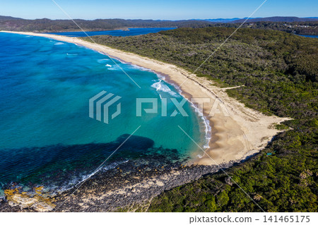 Aerial view of the pristine coastline at Celito Beach with the crystal clear waters of the Pacific Ocean, sandy shoreline and Smiths Lake visible in the background on the Mid North Coast of NSW. 141465175
