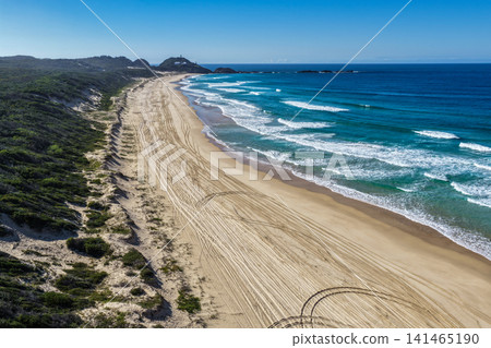 Aerial view of Lighthouse Beach leading towards the historic Seal Rocks Lighthouse, showcasing golden sand, rugged coastline and the clear blue waters of the Pacific Ocean at Seal Rocks, NSW, Aerial view of Lighthouse Beach leading towards the historic Seal Rocks Lighthouse, showcasing golden sand, rugged coastline and the clear blue waters of the Pacific Ocean at Seal Rocks, NSW, 141465190