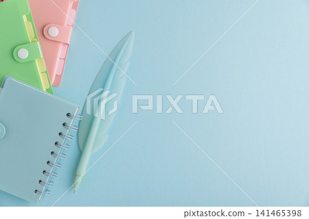 Colorful stationery items with a feather pen on blue background Colorful stationery items with a feather pen on blue background 141465398