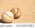 A baseball rolling on a dirt field 141465483