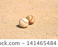 A baseball rolling on a dirt field 141465484