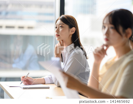 一位女士正在聽講座，同時望著窗外。 141465692
