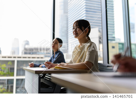 A woman listening to a lecture while gazing at the scenery outside the window. A woman listening to a lecture while gazing at the scenery outside the window. 141465701