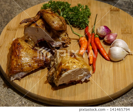Roasted Chicken Pieces with Fresh Garlic, Shallots, Red Chili Peppers and Parsley on Rustic Wooden Cutting Board 141465794