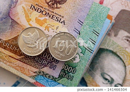 Indonesian rupiah money bills and sen coins pile. Indonesia coins on banknotes of IDR currency 141466304