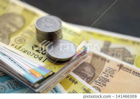 Indian rupee money bills and paisa coins pile on table. India coins on banknotes of INR currency Indian rupee money bills and paisa coins pile on table. India coins on banknotes of INR currency 141466309