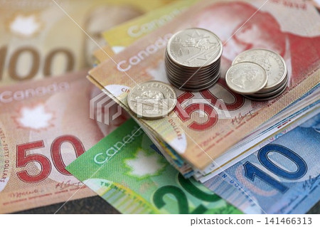 Canadian dollar money bills and cent coins pile on table. Canada coins on banknotes of CAD currency Canadian dollar money bills and cent coins pile on table. Canada coins on banknotes of CAD currency 141466313