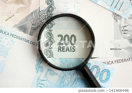 Brazilian reais banknotes and magnifying glass. The current Brazil real money bills and loupe Brazilian reais banknotes and magnifying glass. The current Brazil real money bills and loupe 141466496
