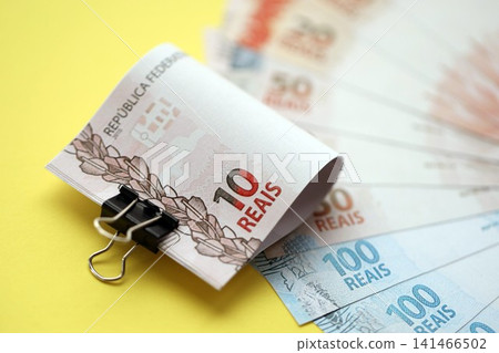 Close up of brazilian reais money bills in big amount on yellow. Pile of Brazil real currency Close up of brazilian reais money bills in big amount on yellow. Pile of Brazil real currency 141466502