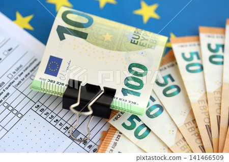 European euro currency money notes bunch on tax form and European union blue flag close up 141466509