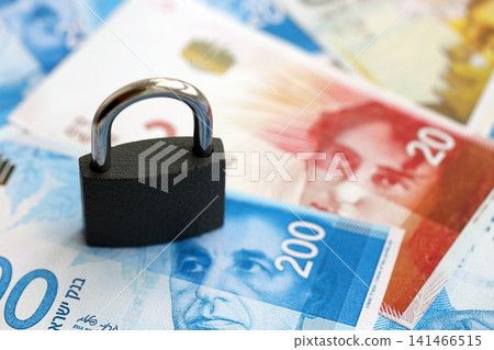 Israel New Shekels banknotes and padlock. The current Israel money bills and lock lies on table Israel New Shekels banknotes and padlock. The current Israel money bills and lock lies on table 141466515
