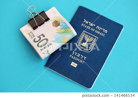 Israel New Shekels banknotes and passport on blue background. The current Israel money bills Israel New Shekels banknotes and passport on blue background. The current Israel money bills 141466534