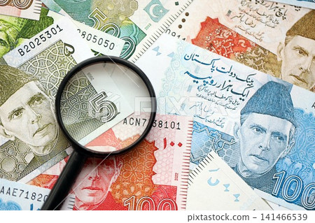 Pakistan rupees banknotes and magnifying glass. The current Pakistan money bills with loupe Pakistan rupees banknotes and magnifying glass. The current Pakistan money bills with loupe 141466539