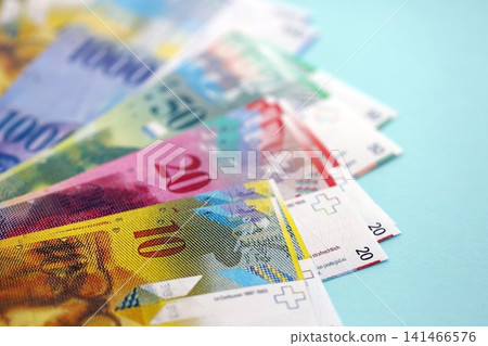 Swiss franc banknotes on blue background. The current francs money bills lies in big amount Swiss franc banknotes on blue background. The current francs money bills lies in big amount 141466576