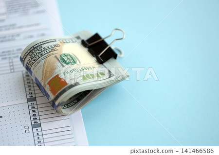 Big amount of United States dollar bills on table with 1040 tax return form Big amount of United States dollar bills on table with 1040 tax return form 141466586