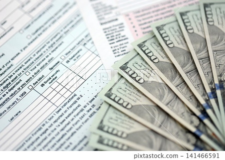 Big amount of United States dollar bills on table with tax return form close up 141466591