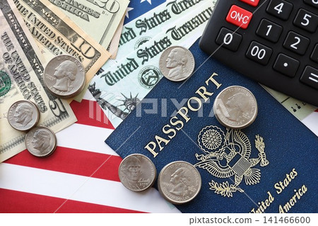 American US dollars money bills, passport and calculator on American flag close up American US dollars money bills, passport and calculator on American flag close up 141466600