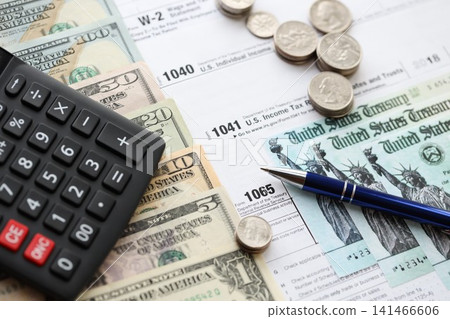 American US dollars money bills and coins with pen and calculator on IRS tax form blanks American US dollars money bills and coins with pen and calculator on IRS tax form blanks 141466606