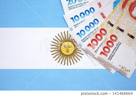 Argentine pesos money bills in big amount lies on Argentina flag close up Argentine pesos money bills in big amount lies on Argentina flag close up 141466664