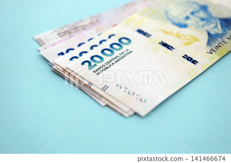 Argentine pesos money bills in big amount lies on teal color table close up Argentine pesos money bills in big amount lies on teal color table close up 141466674
