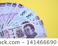 Mexican pesos money bills in big amount lies on yellow color table close up 141466690
