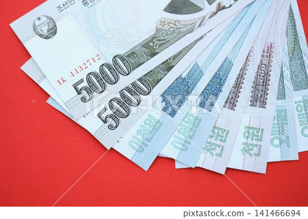 North Korean won money bills in big amount lies on red color table close up 141466694