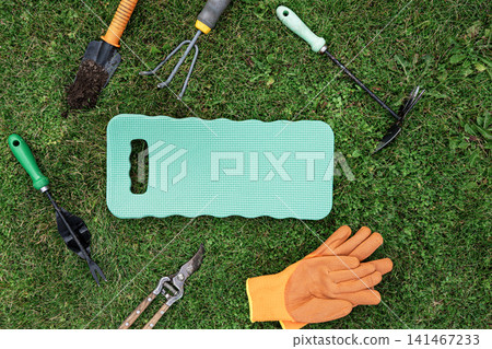 Gardening tools and kneeling pad on grass flat lay with copy space Gardening tools and kneeling pad on grass flat lay with copy space 141467233