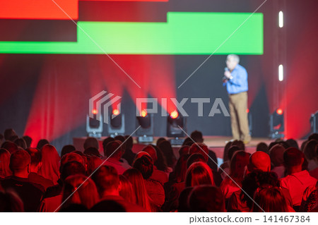 Speaker on stage with vibrant red and green lighting 141467384