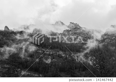 Wide monochrome view of stratified Piz de Pares cliffs and scattered fog 141467442
